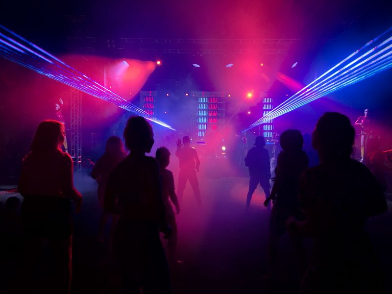 Dancers silhouetted in pink and blue lasers