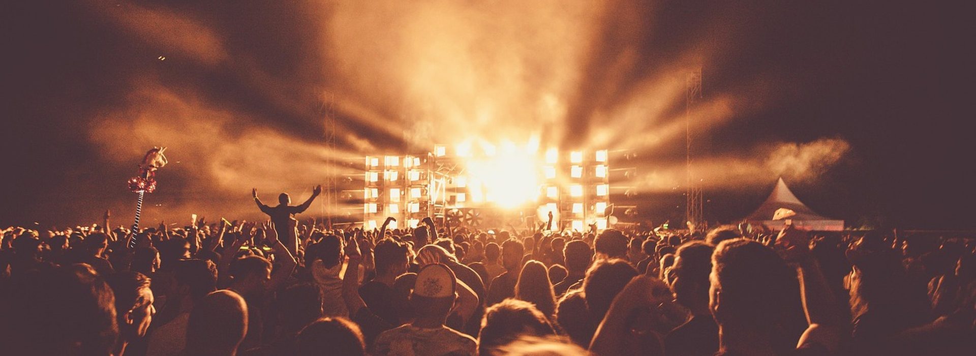 Festival crowd facing a bright stage at night
